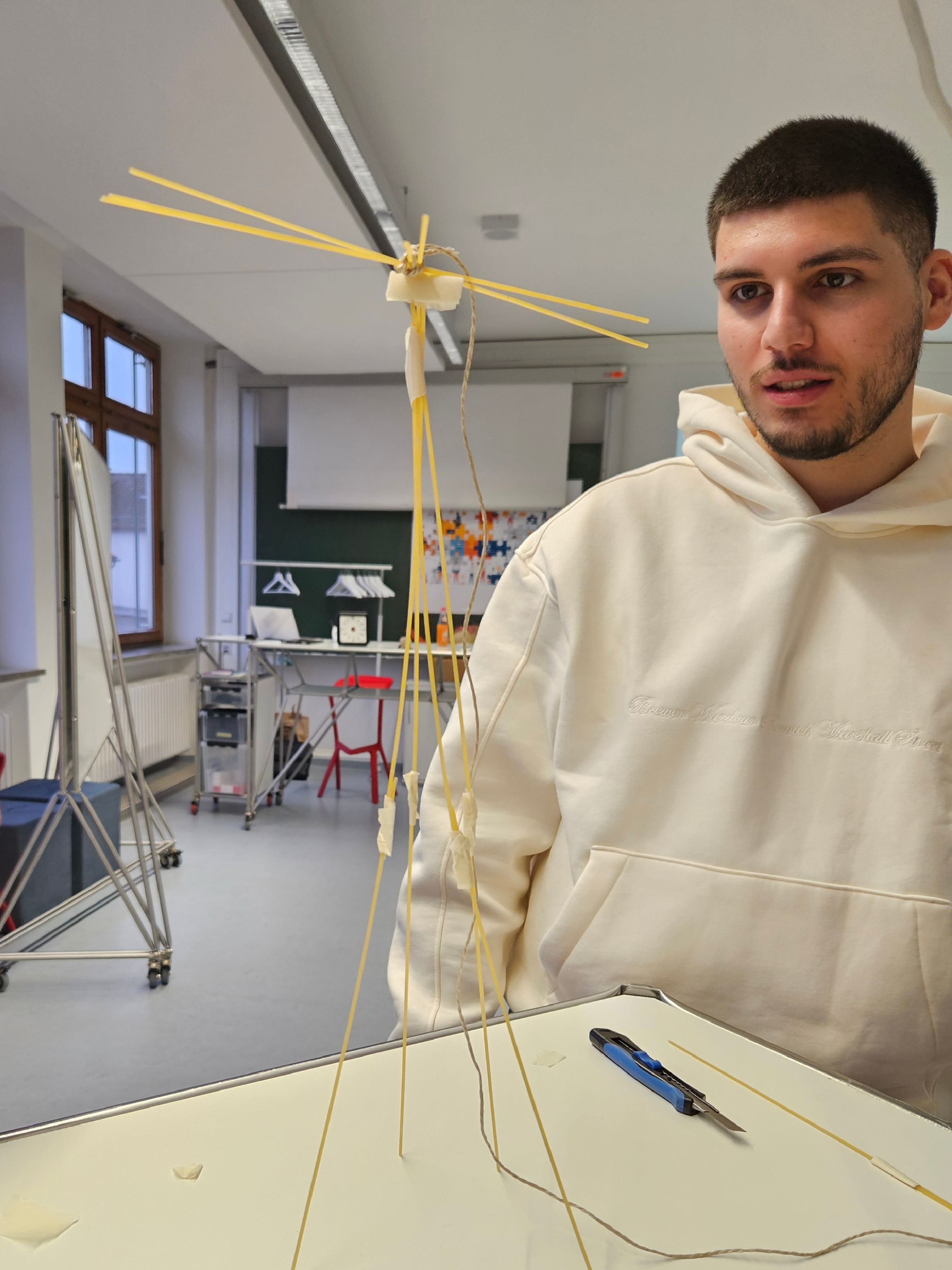 Student steht vor einem Turm aus Spaghetti und Marshmallow