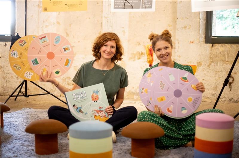 Zwei Frauen zeigen Bücher und lachen in die Kamera