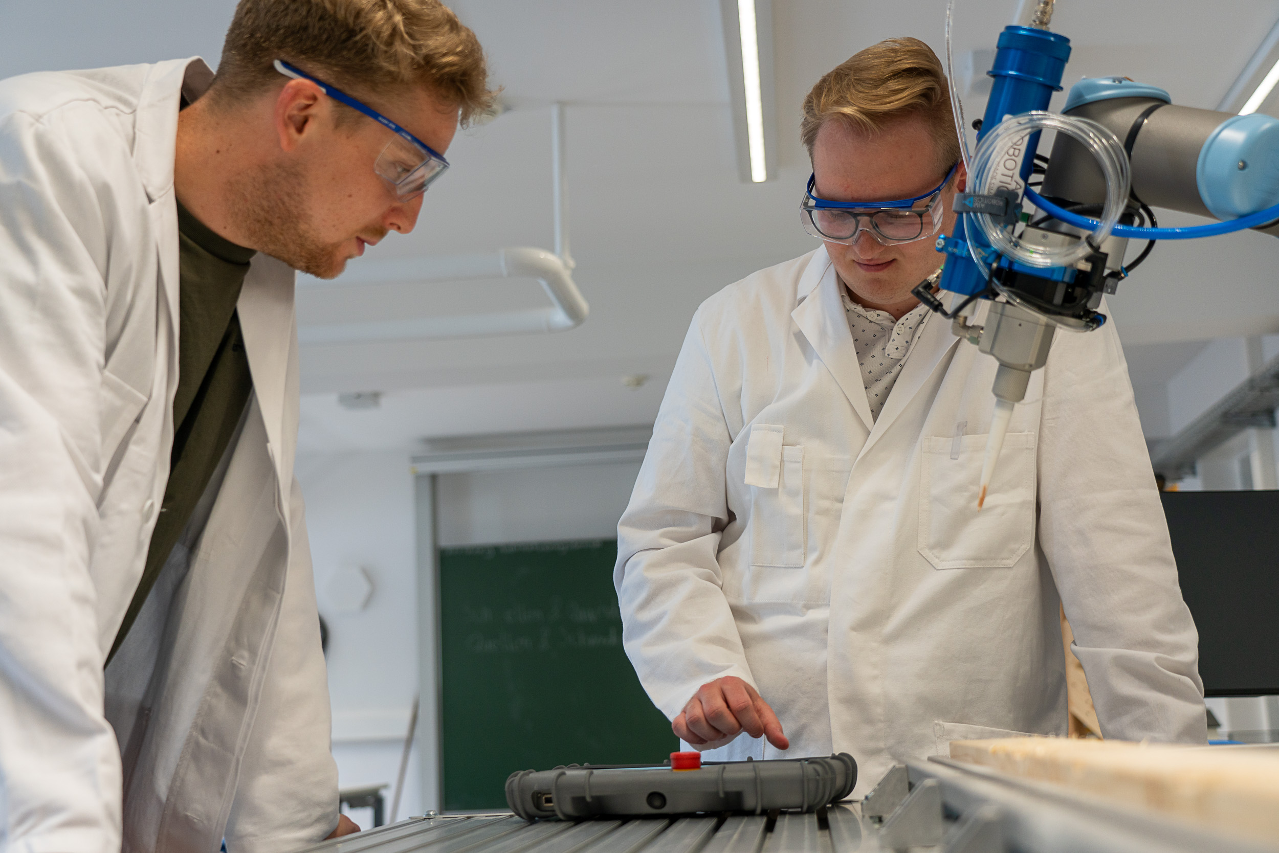 Zwei Männer im Labor arbeiten an einem Roboterarm