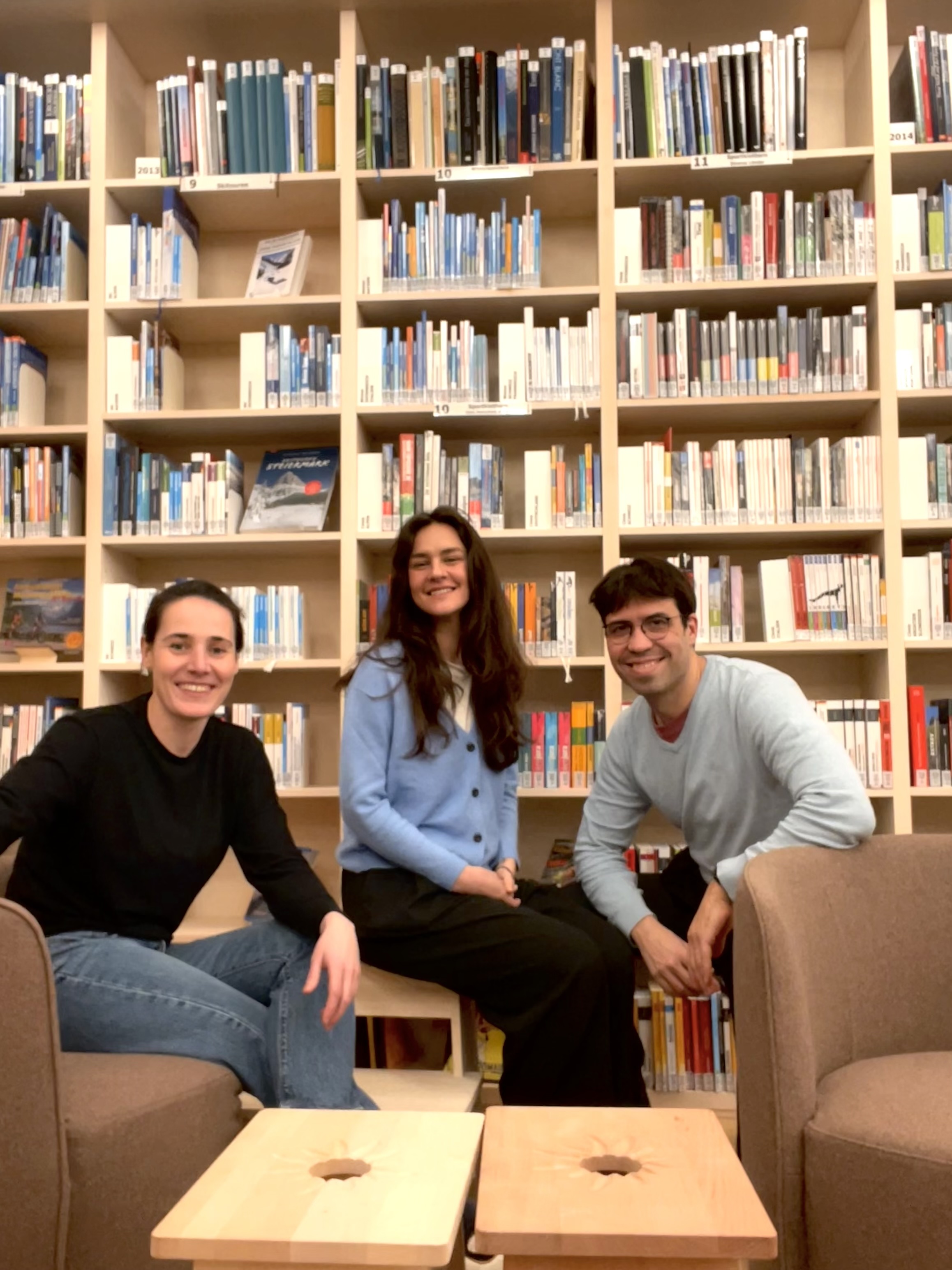 Drei Personen sitzen vor einer Bibliothek