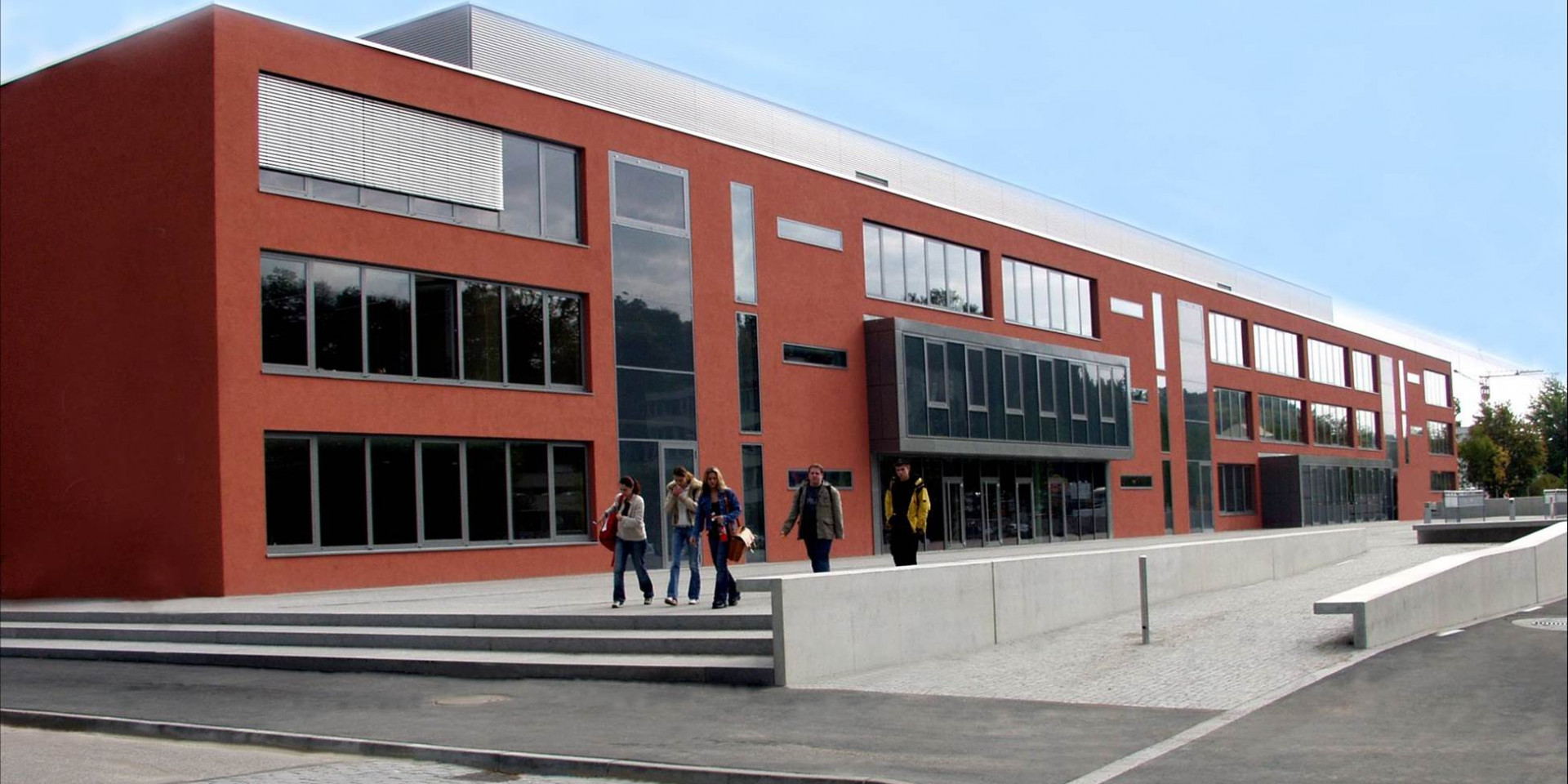 Rotes Gebäude, Schule, mit Personen davor
