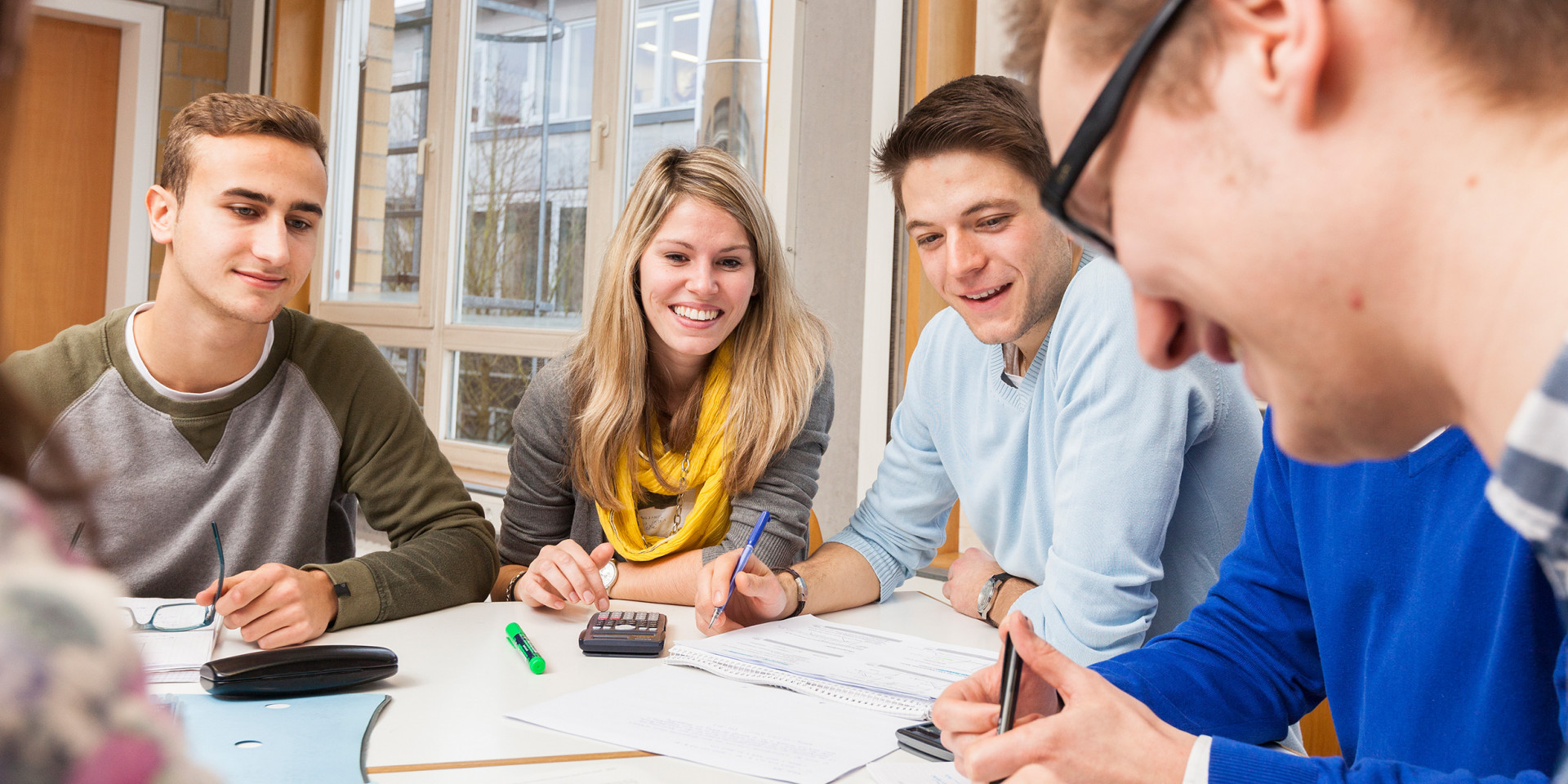 Gruppe von Studierenden, die motiviert bei einer Gruppenarbeit sind.