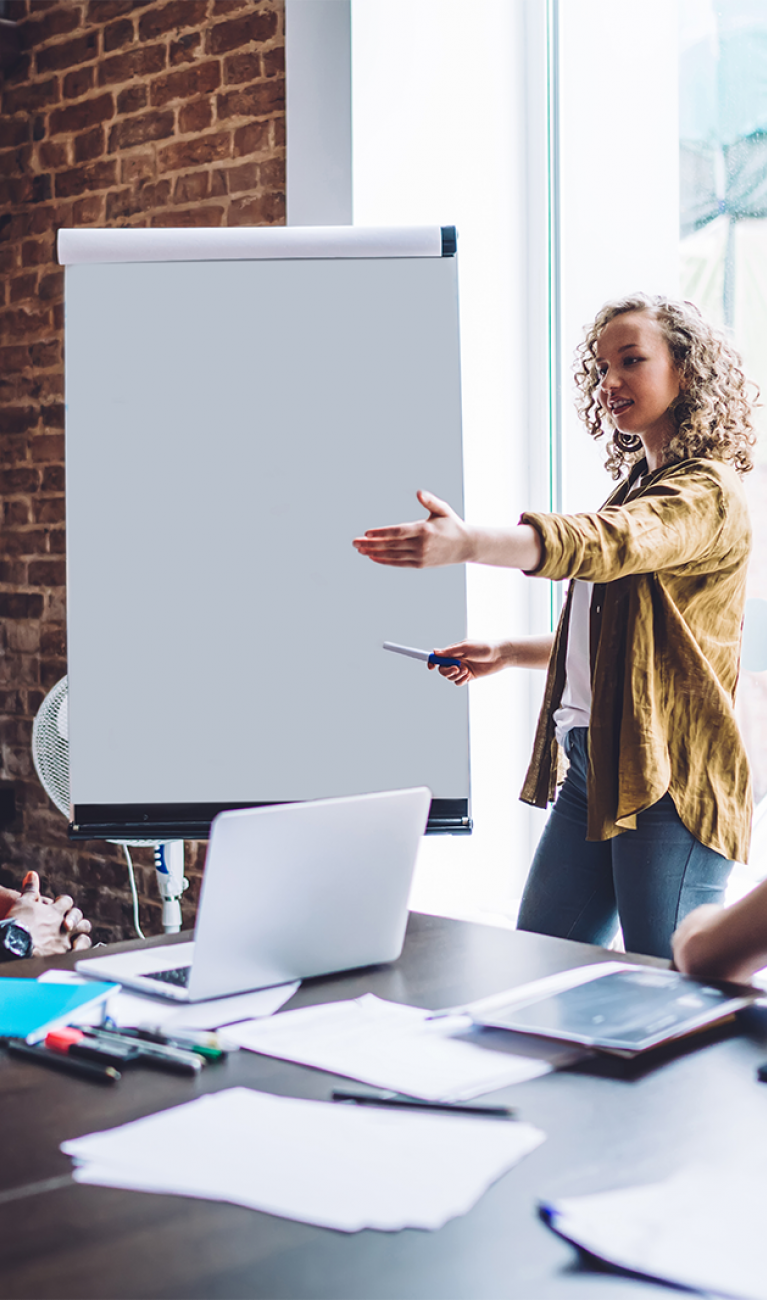 Vier Studierende unterschiedlicher Nationalitäten sitzen in einem modernen Besprechungsraum mit Flipchart und diskutieren