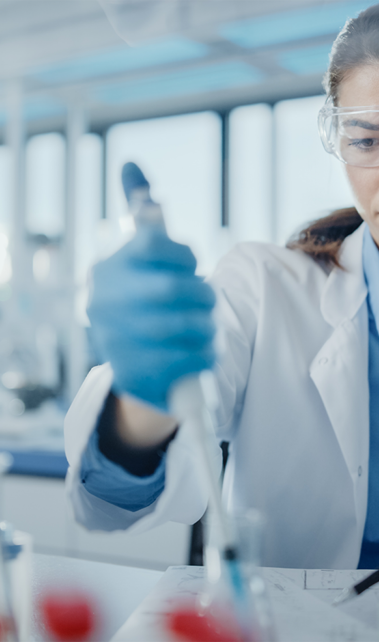 Wissenschaftlerin mit Schutzbrille verwendet eine Mikropipette für Testanalysen in einem modernen Labor für Biotechnologie und Mikrobiologie-Entwicklung