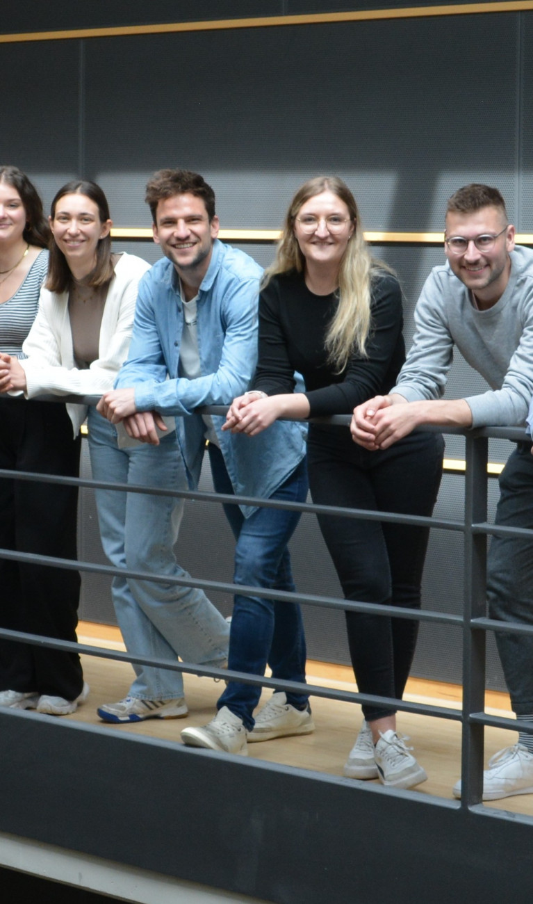 Gruppe von Menschen lehnt an Stahlgeländer in Treppenhaus