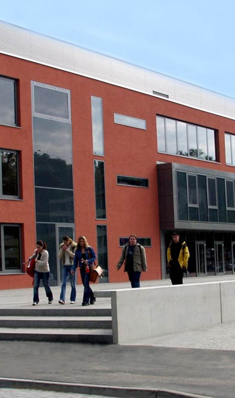 Rotes Gebäude, Schule, mit Personen davor