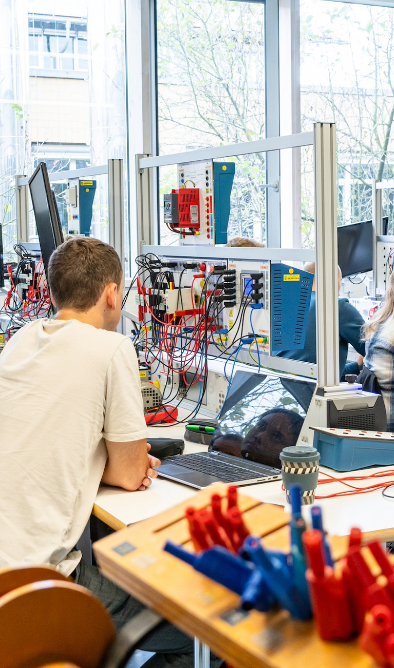 Personen sitzen in einem Labor für elektrische Systeme